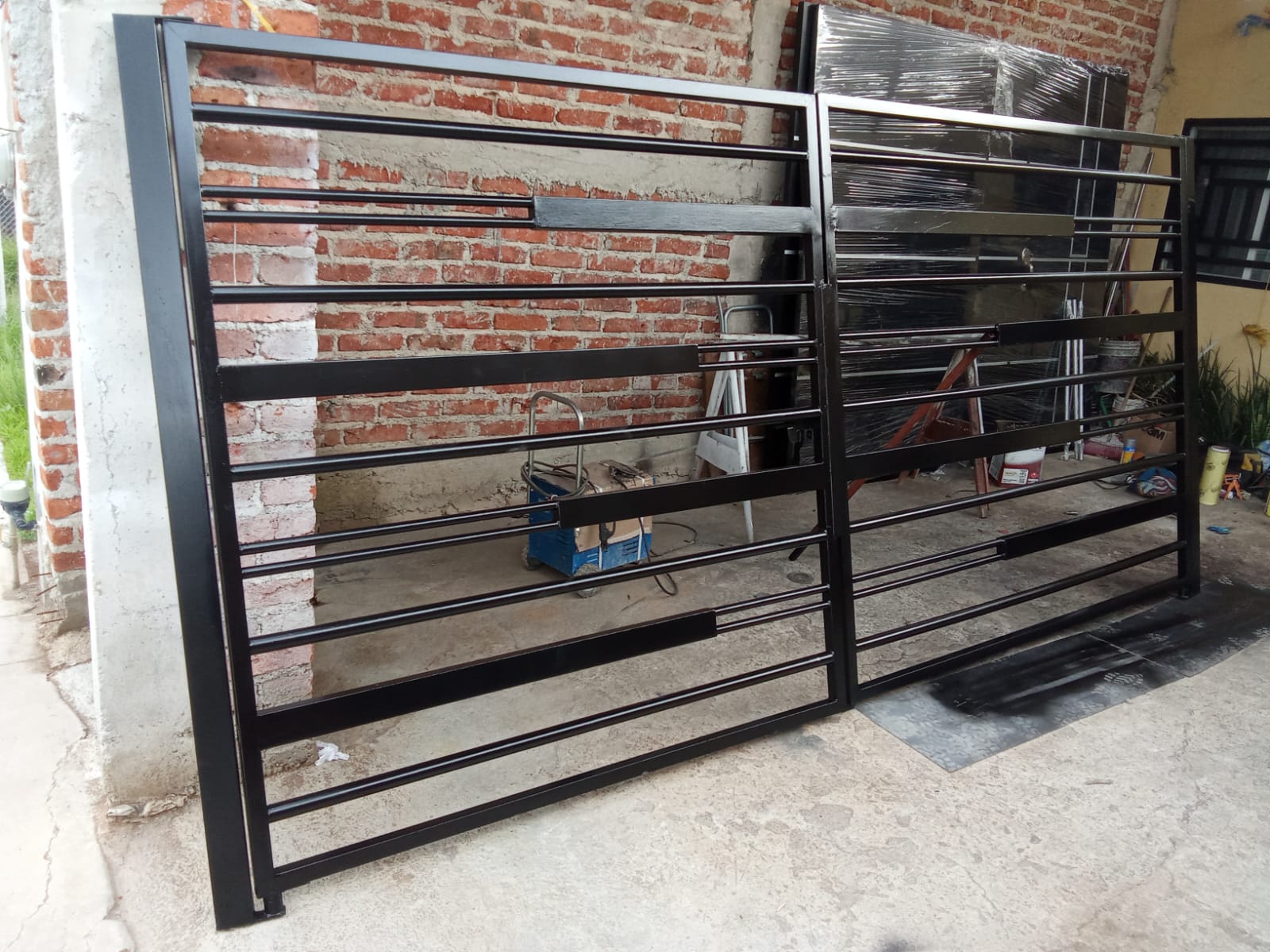 Portón de reja en acabado negro instalado sobre muro de ladrillo