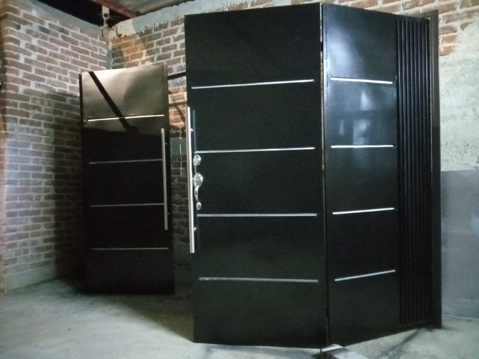Puerta de herrería en acabado negro instalada en esquina de fachada